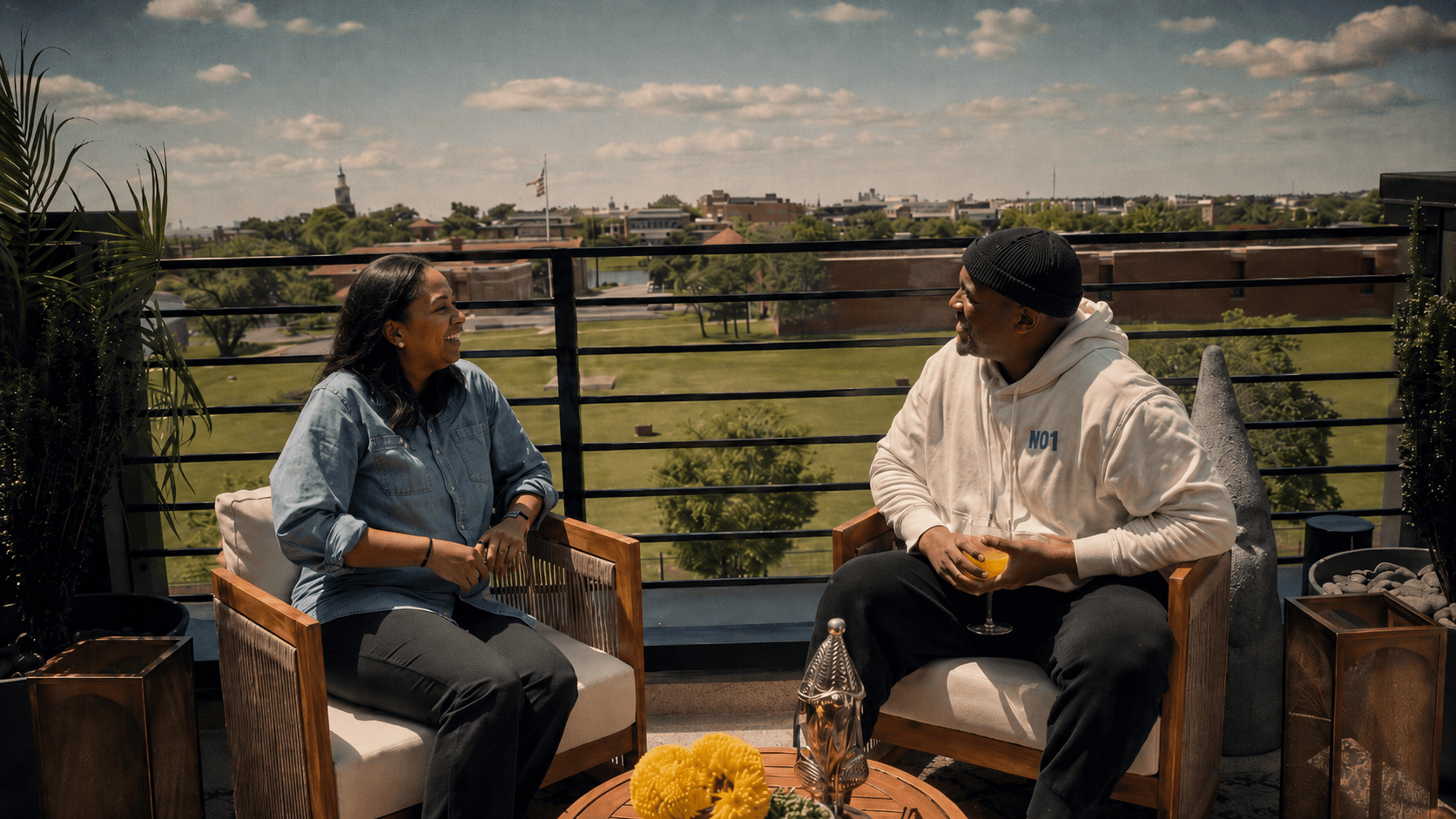 Shannon Travis in conversation with a guest on the Pond & Perch rooftop, the Washington, DC skyline behind them.
